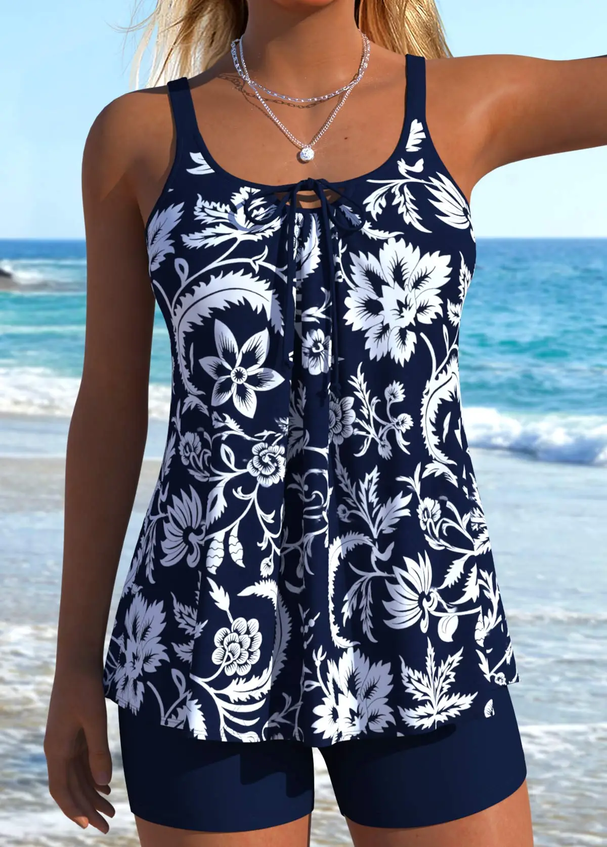 Woman in floral swimsuit standing on beach with ocean waves in background