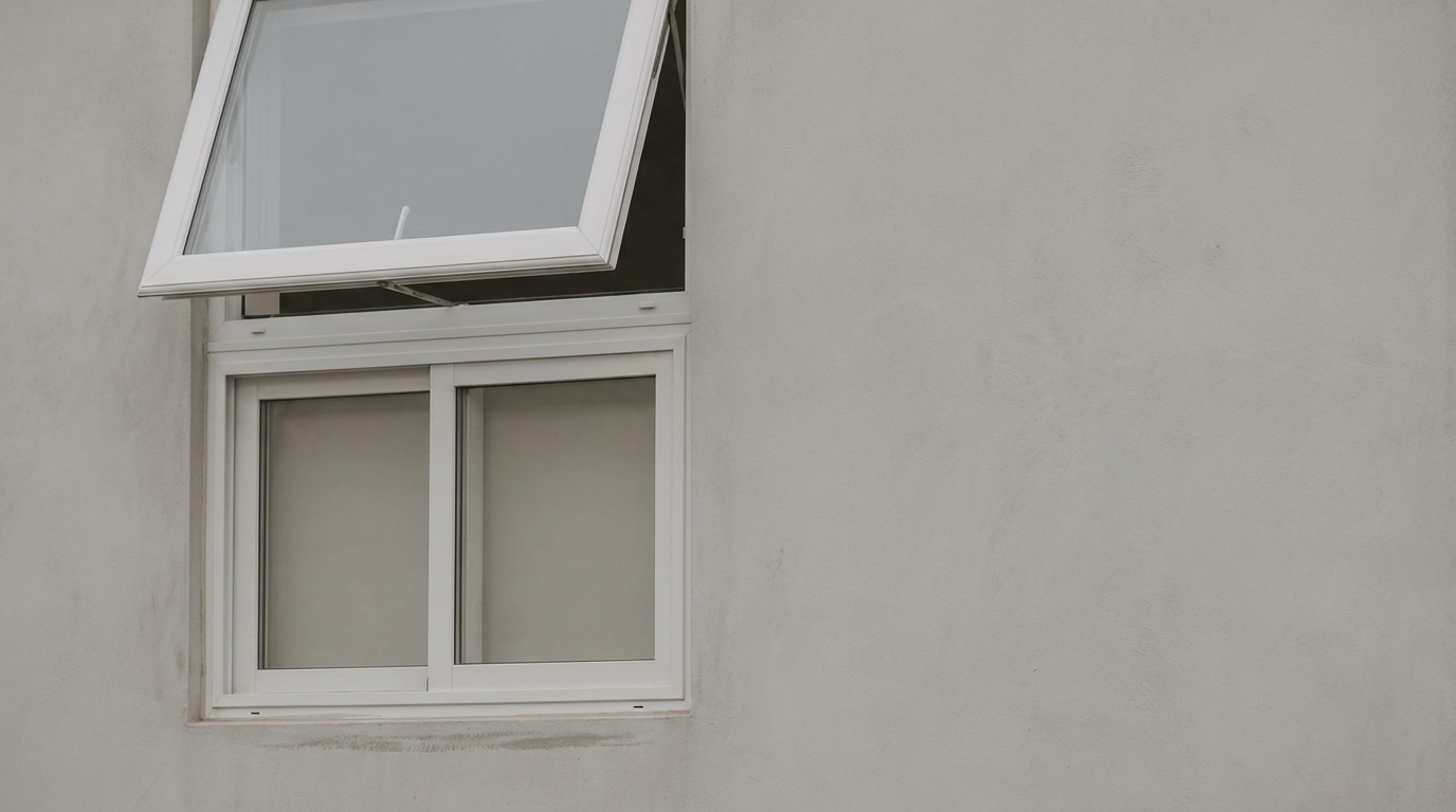 Open white-framed window on plain beige wall in daylight